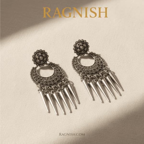 Polished silver RAGNISH earrings with pointed spike tassels hanging from a detailed half-moon shape.