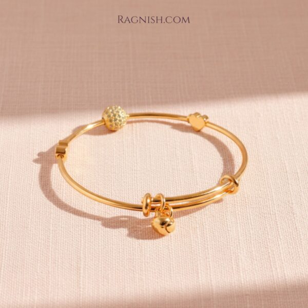 Gold RAGNISH charm bracelet duo on neutral textured background with soft lighting.