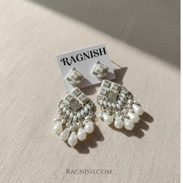 Close-up of traditional Indian bridal-style jhoomar earrings with dangling teardrop pearls.