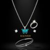 RAGNISH luxury jewelry set with iridescent blue and green butterfly pendant necklace, silver solitaire ring, open bangle, and square stud earrings on a black background.