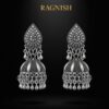 Close-up of oxidized metal jhumka earrings by RAGNISH, highlighting the detailed floral pattern and dangling silver bead charms.