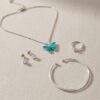 High-quality e-commerce photo of a full RAGNISH silver jewelry collection including a butterfly pendant, diamond simulant ring, and minimalist bracelet.